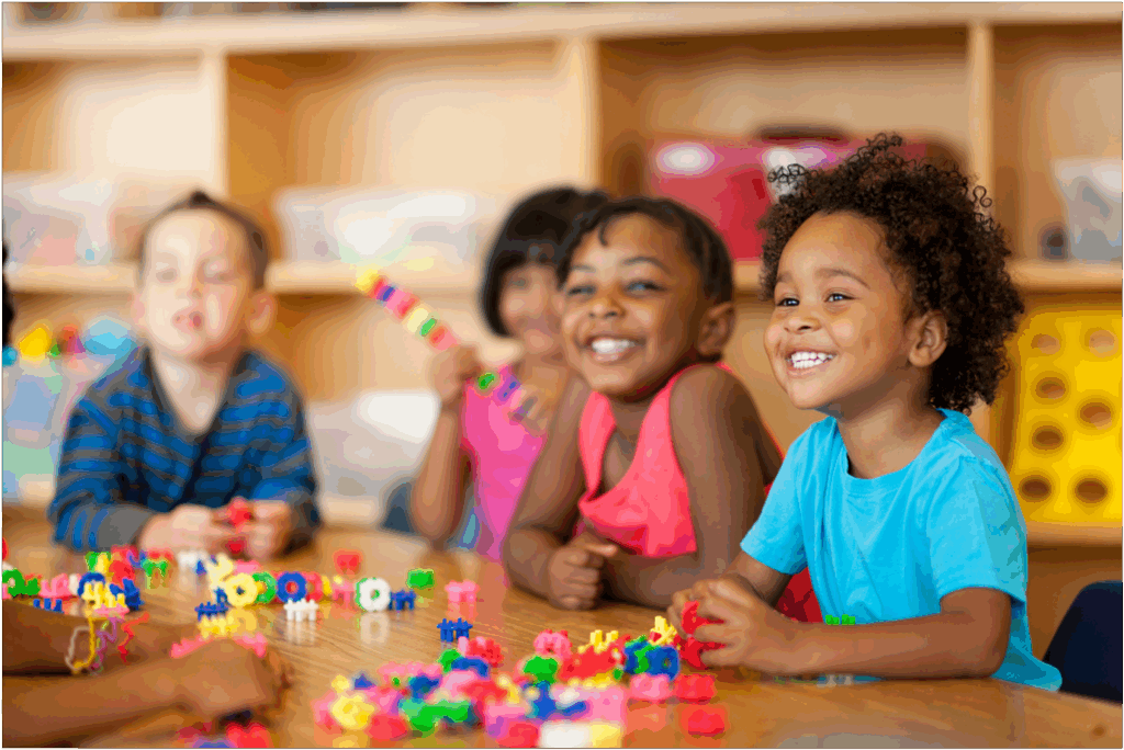 Children smiling at learning table.